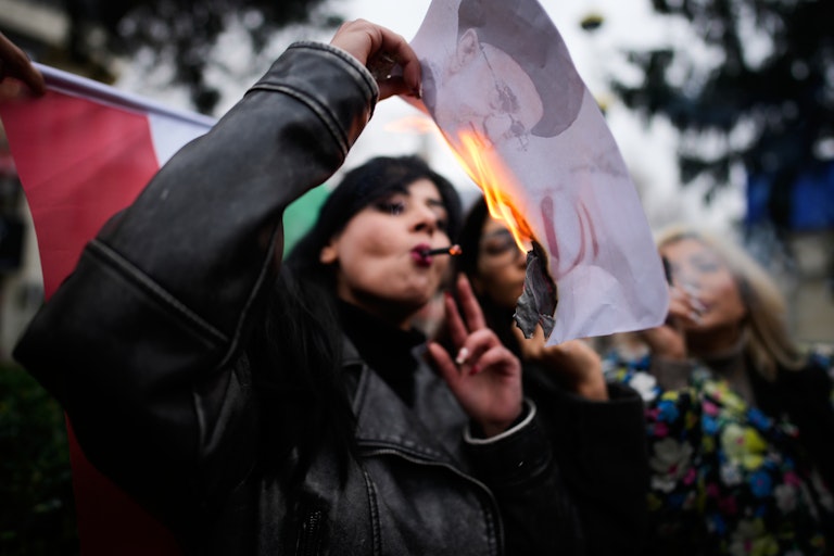 Una manifestante fuma un cigarrillo después de encenderlo en un cartel en llamas que representa al líder supremo iraní, el ayatolá Alí Jamenei, una imagen que se ha convertido en el símbolo de la revuelta actual, durante una concentración en apoyo a las manifestaciones antigubernamentales en Irán, en Yalova, Turquía, el 16 de enero de 2026.