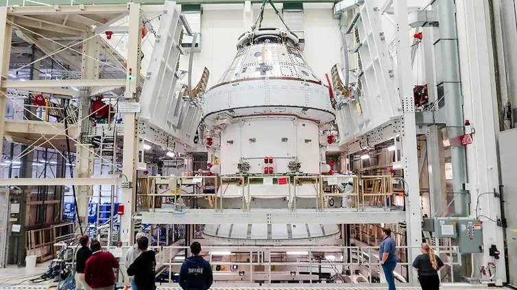 Una nave espacial en una nave de trabajo de la NASA con operarios que la observan