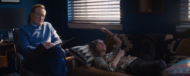 Lo que 'Si tuviera piernas te patearía' nos dice sobre la maternidad y el sacrificio ingrato 1 Un hombre pelirrojo y gafas parece dolido mientras una mujer se tumba en un sofá y habla.