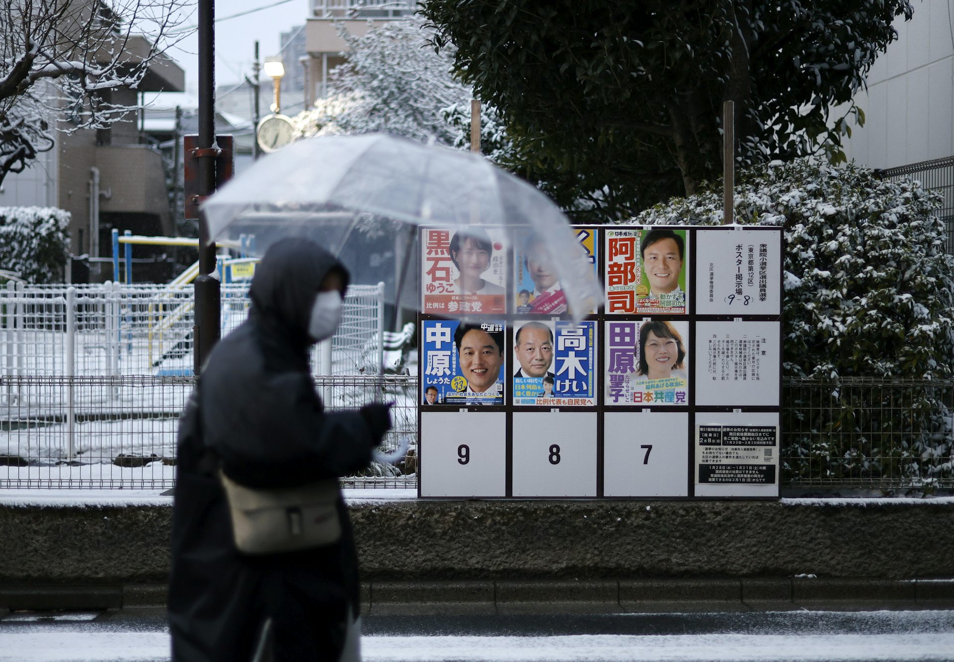 A person walks near a board in Tokyo displaying posters of local candidates for Japan's lower house election.