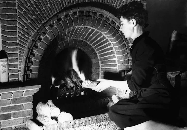 A woman builds a wood fire.