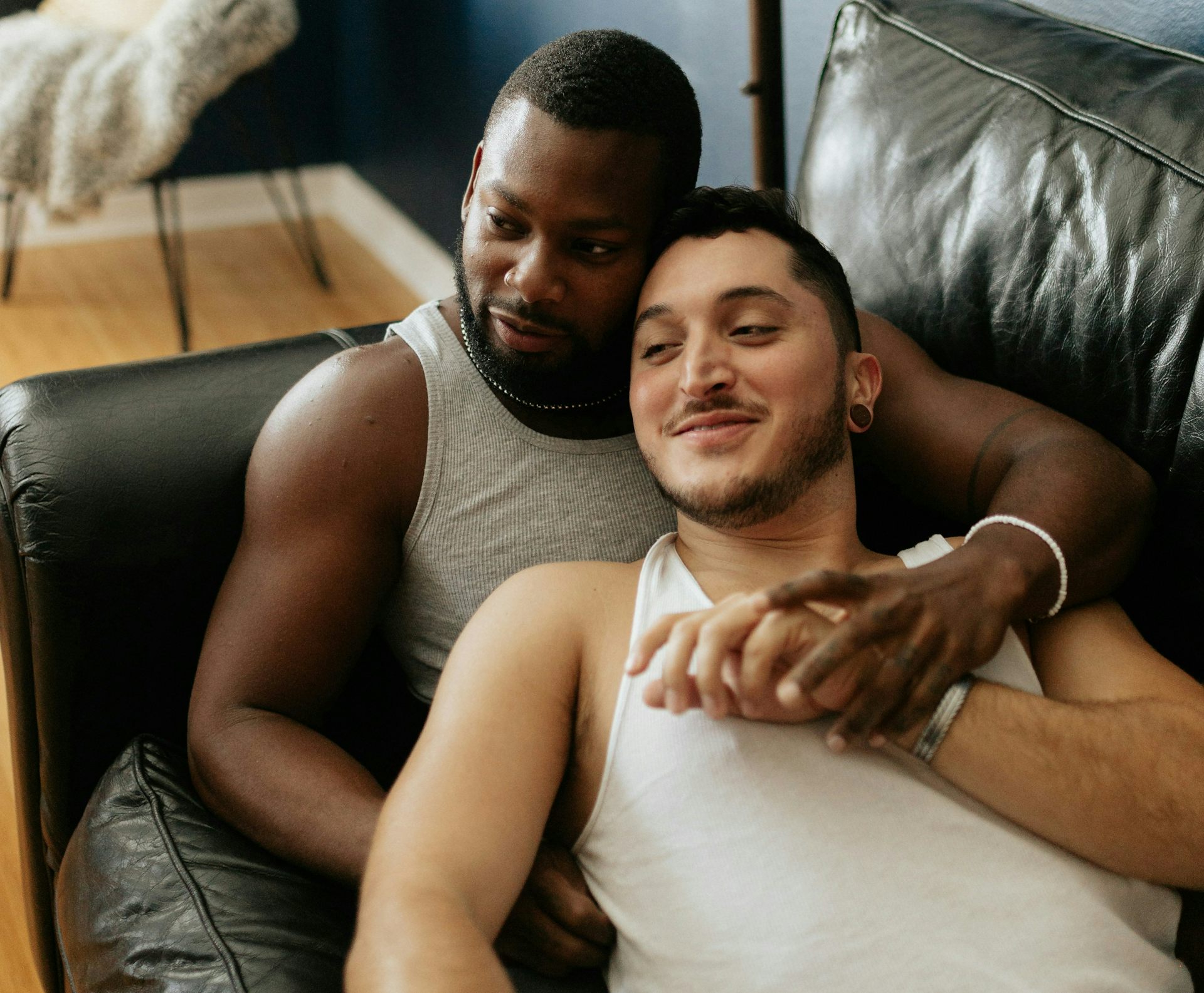 Dua laki-laki sedang berpelukan di sofa sambil menonton TV.