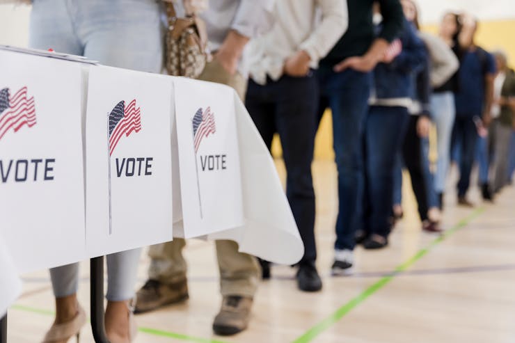 Voters line up to vote in a gym.
