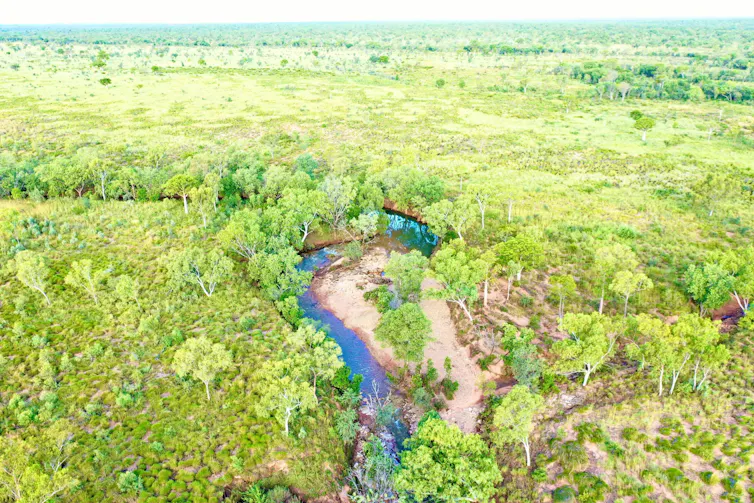 green landscape and creek in foreground, aerial shot.
