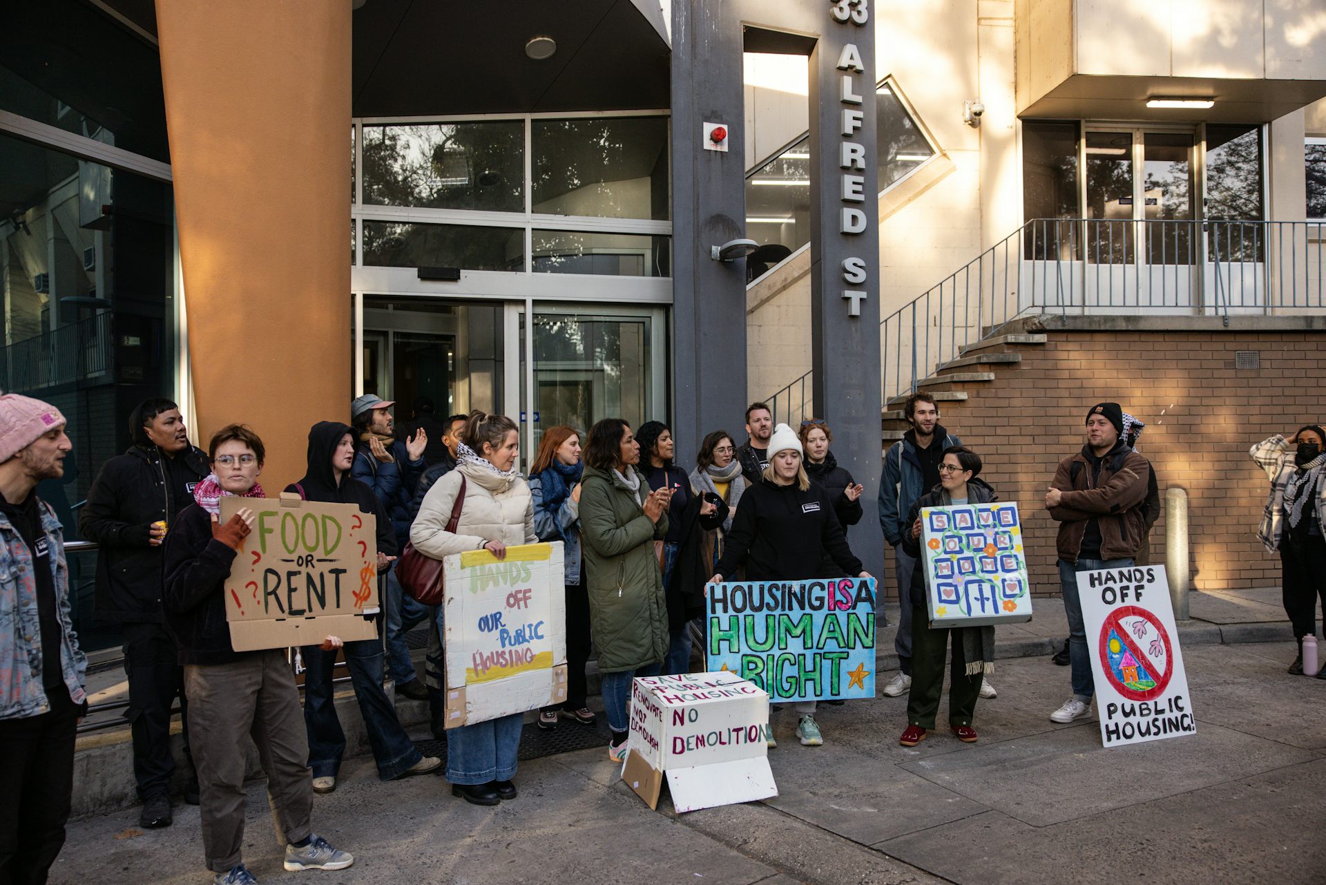A crowd holding Hands off public housing signs outside a public housing tower due for demolition – which has been delayed by an ongoing court appeal