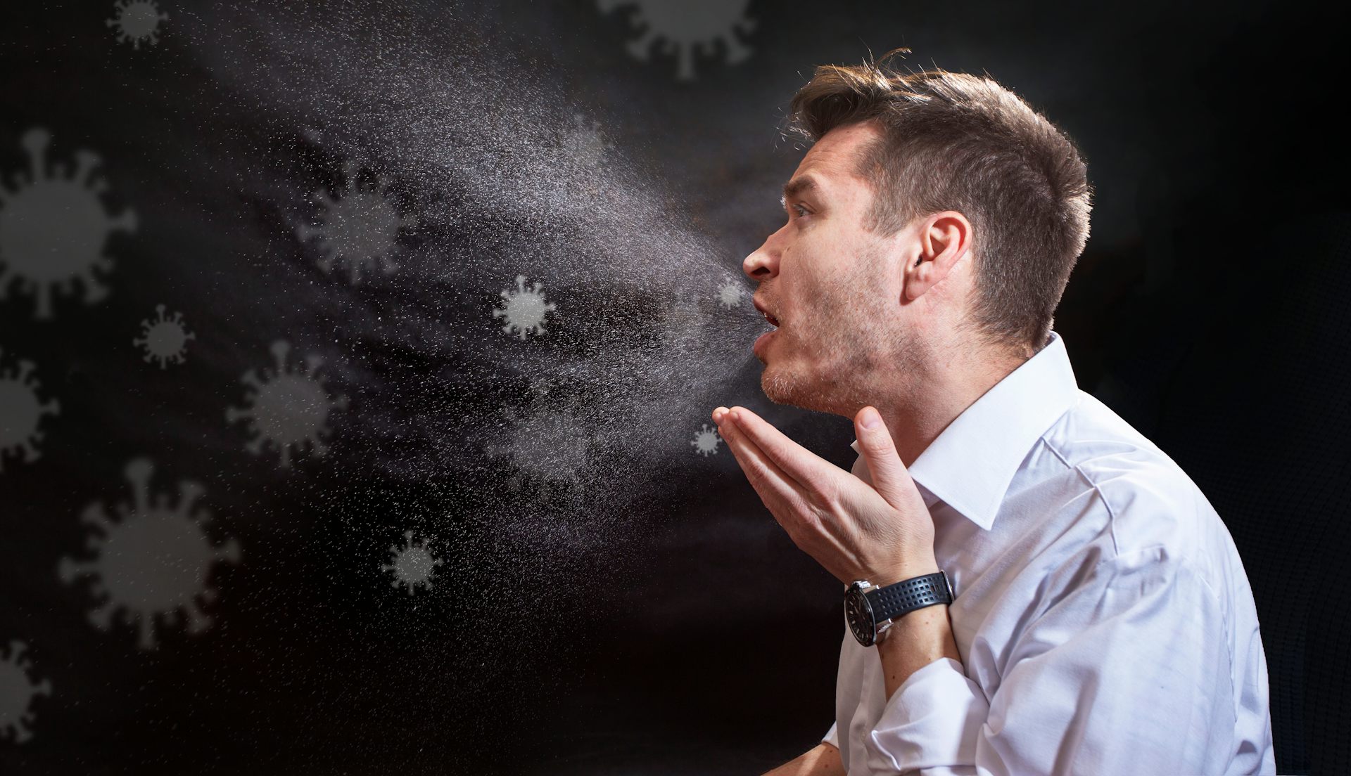 Une illustration montre un homme qui tousse et émet des particules virales dans l'air.