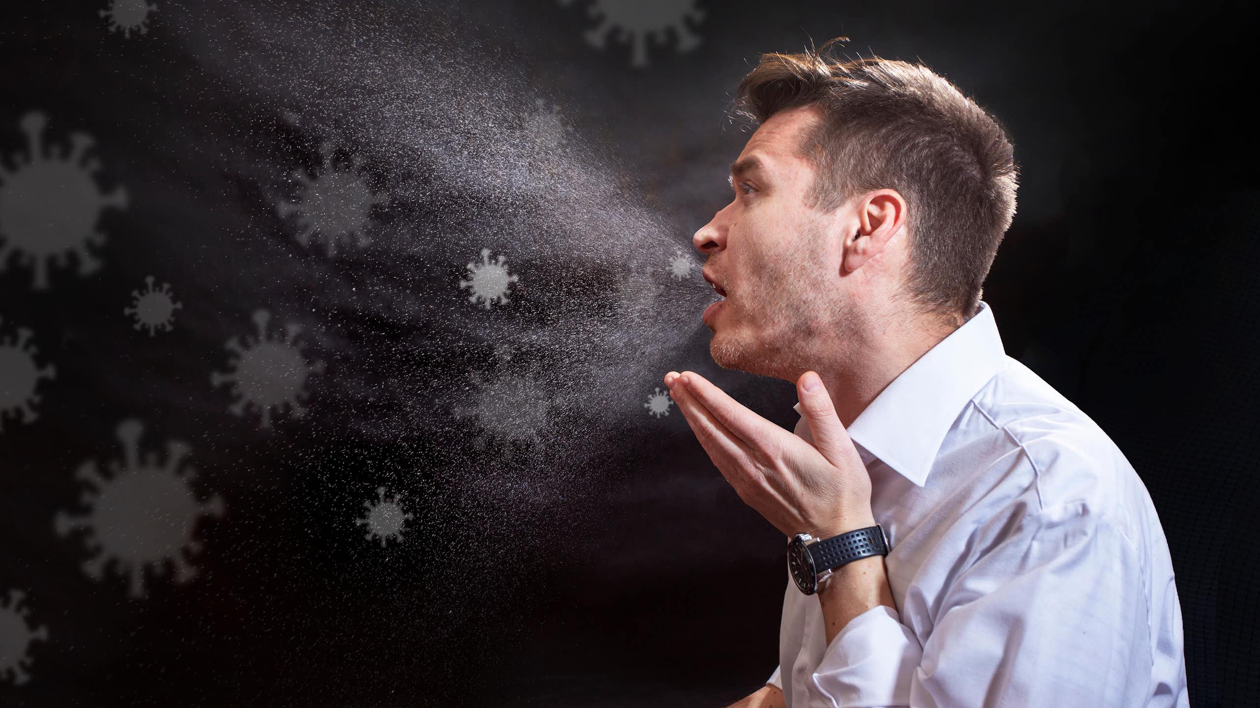 Une illustration montre un homme qui tousse et émet des particules virales dans l'air.