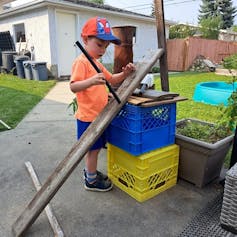 Cómo el juego de los niños con objetos cotidianos puede fomentar las habilidades necesarias para el éxito en STEM 2 Niño de pie con rampa de madera y otros objetos.