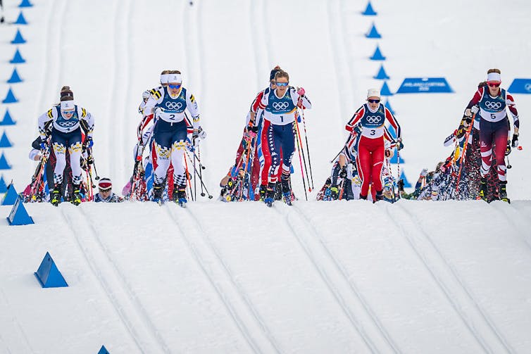Five rows of Olympic skiers race down the hill
