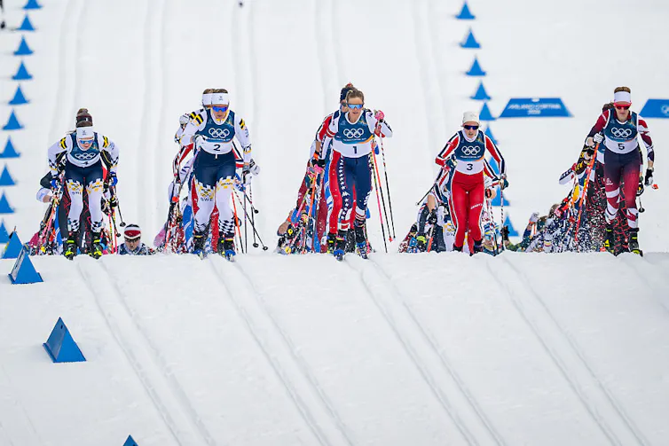 Five rows of Olympic skiiers racing down a hill