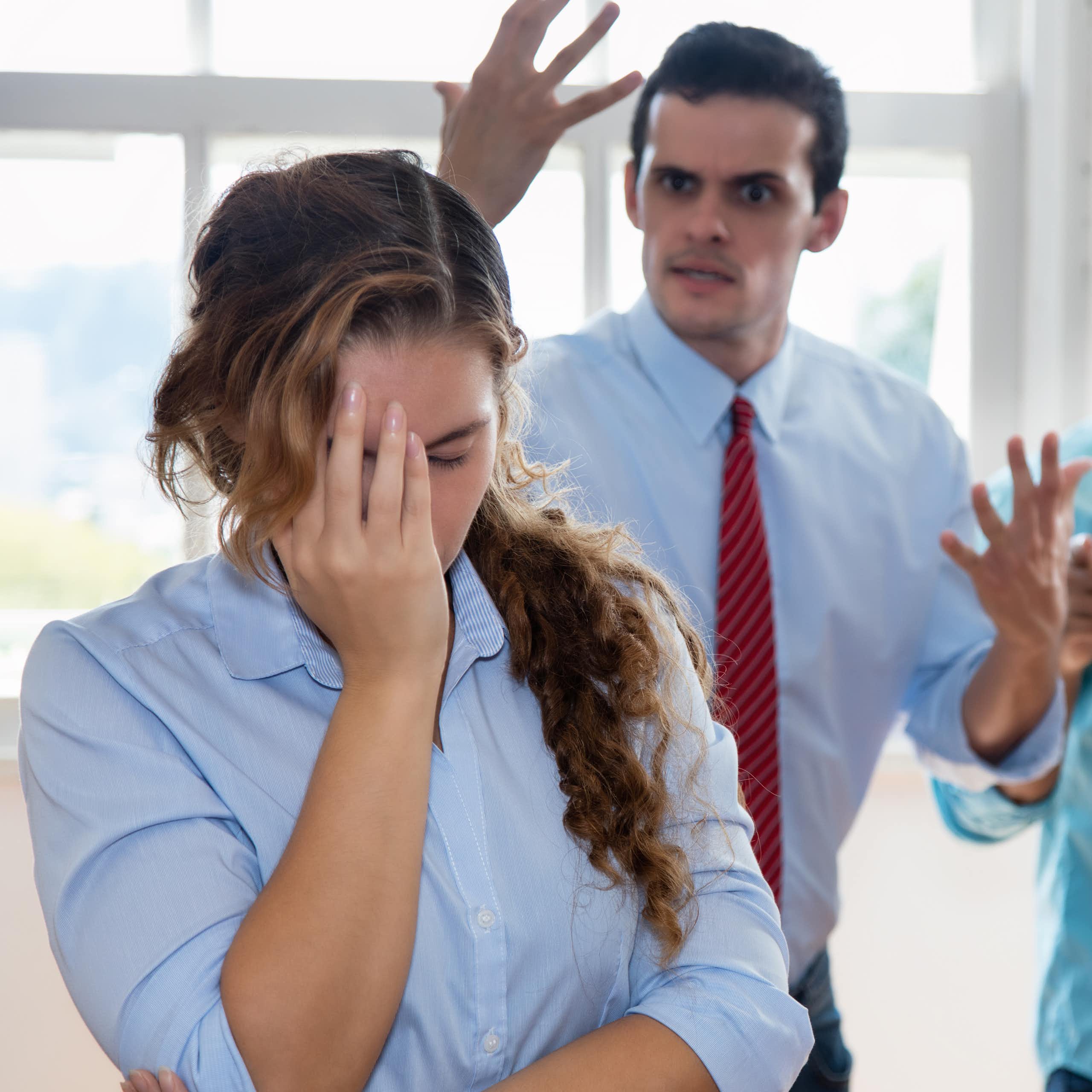 Employée la main sur sa tête avec son patron qui lui crie dessus