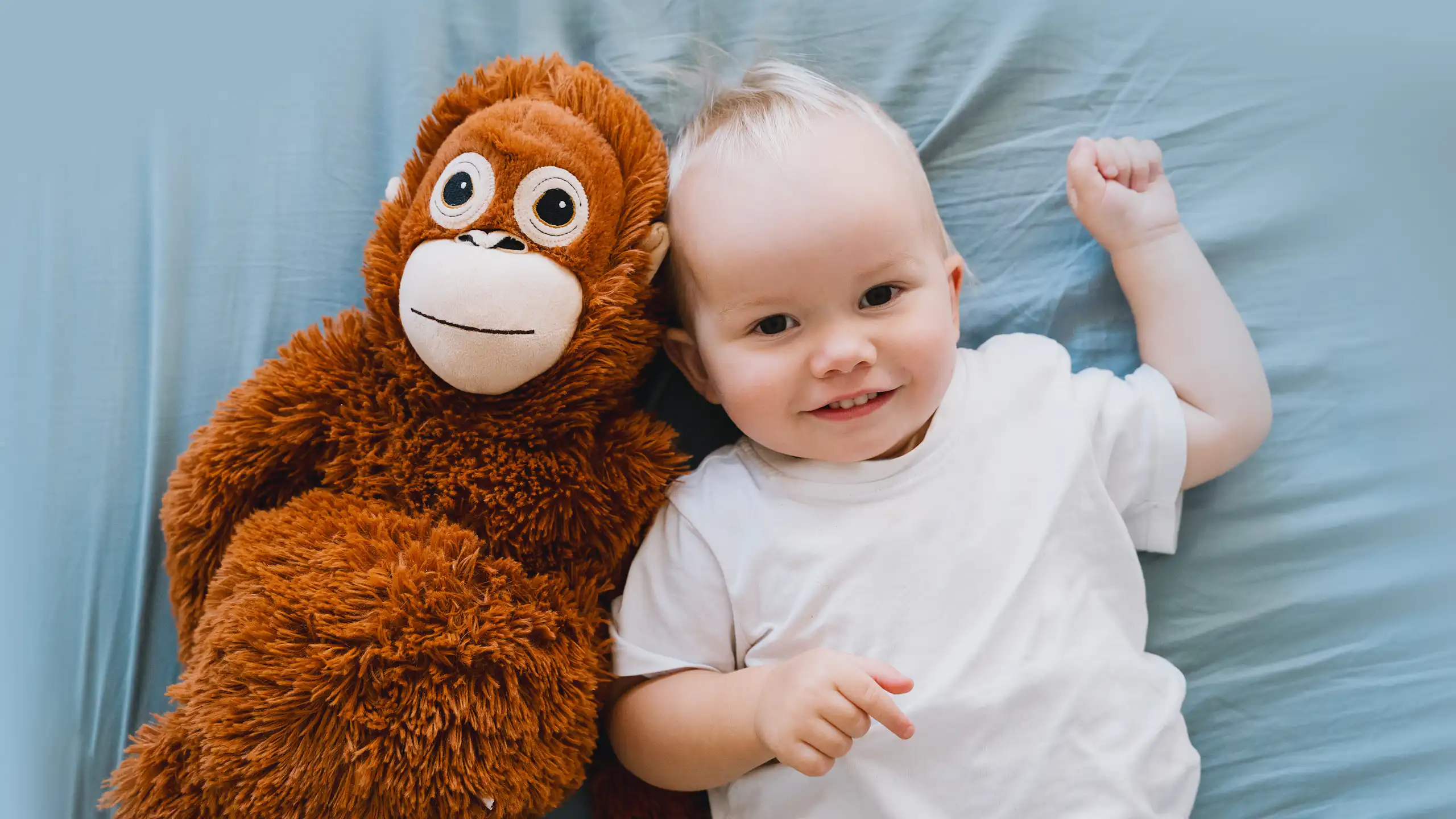 Toddler lying on bed next to monkey toy
