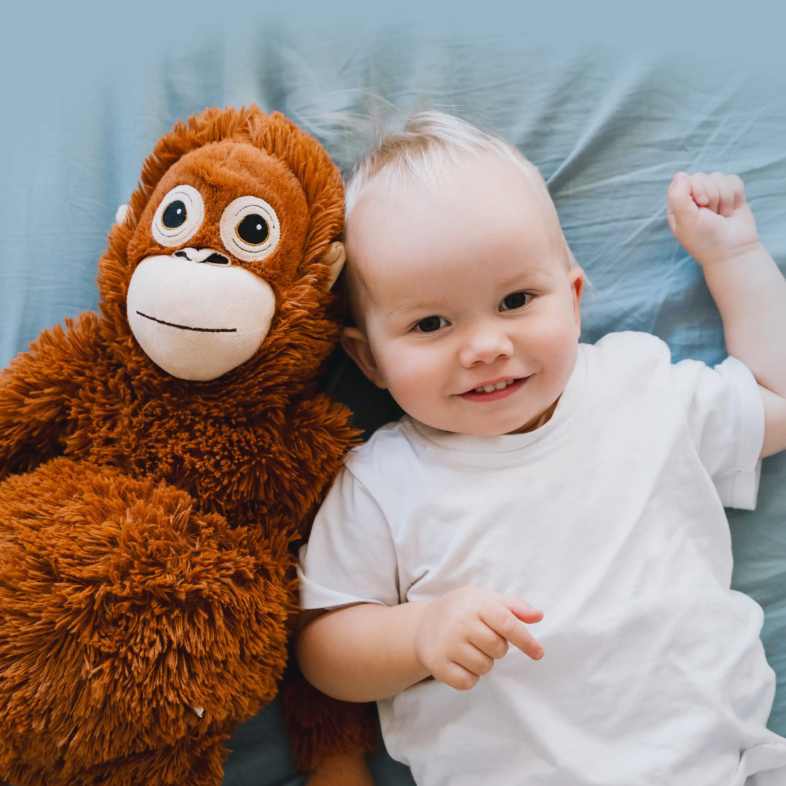Toddler lying on bed next to monkey toy