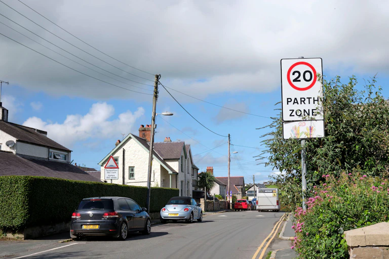 A view of a town road, with a 20mph limit sign in English and Welsh.