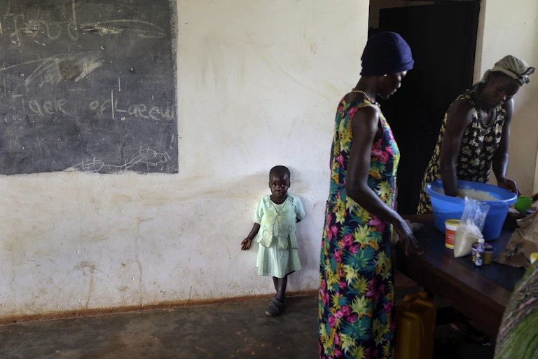 Two women and a young girl standing in a kitchen completing chores.