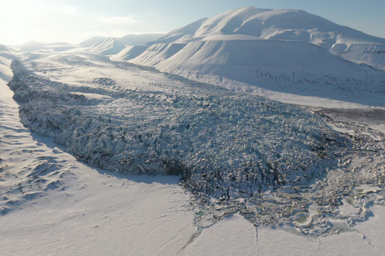 A broken-up glacier extending into a frozen fjord