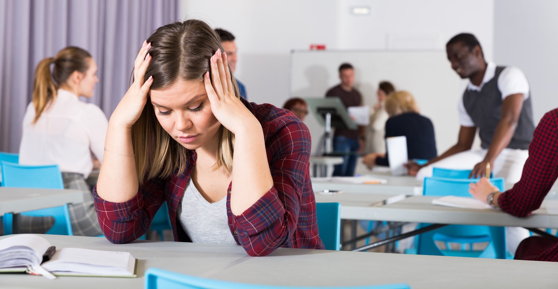 Una joven con gesto de desesperación en un aula.