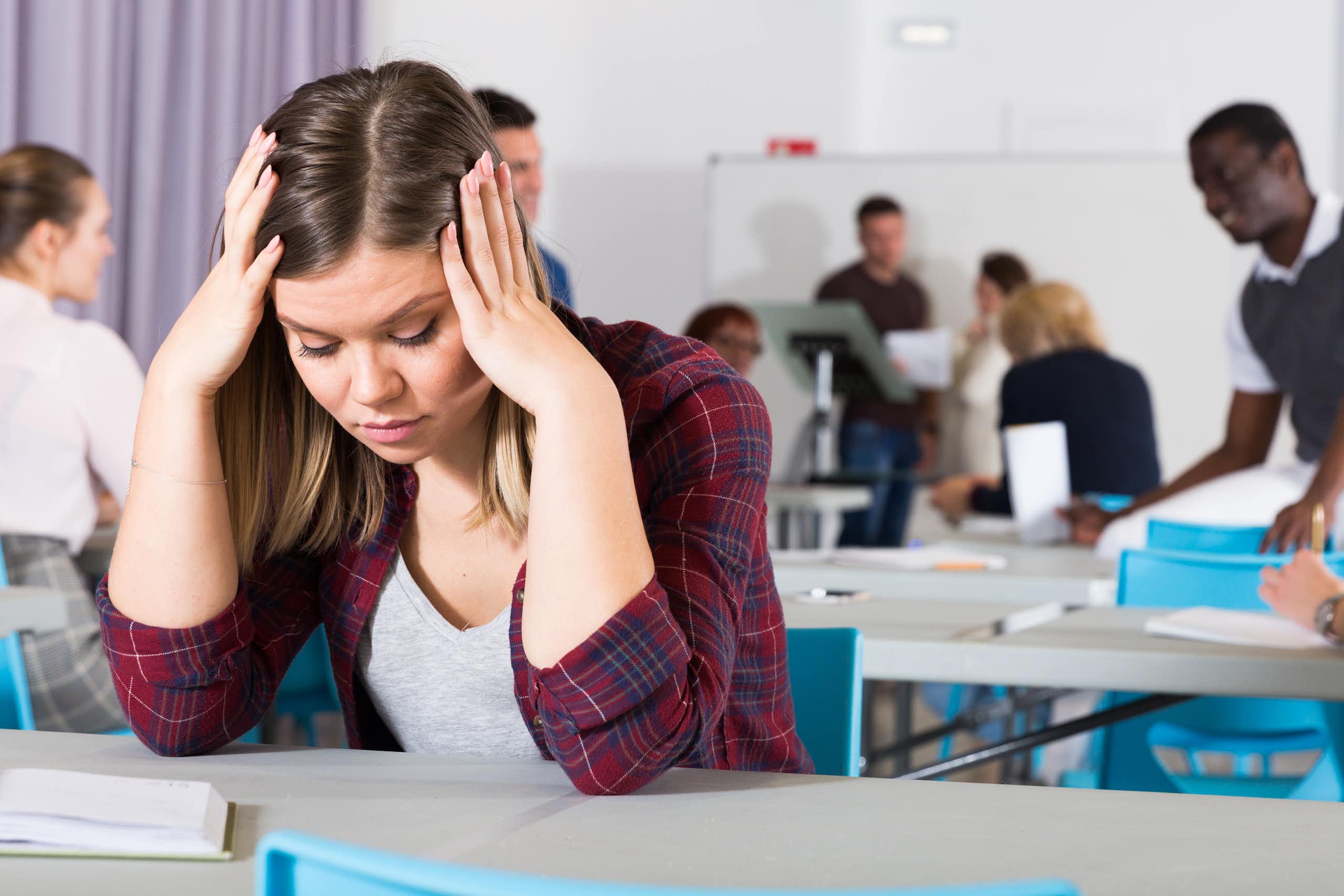 Una joven con gesto de desesperación en un aula.