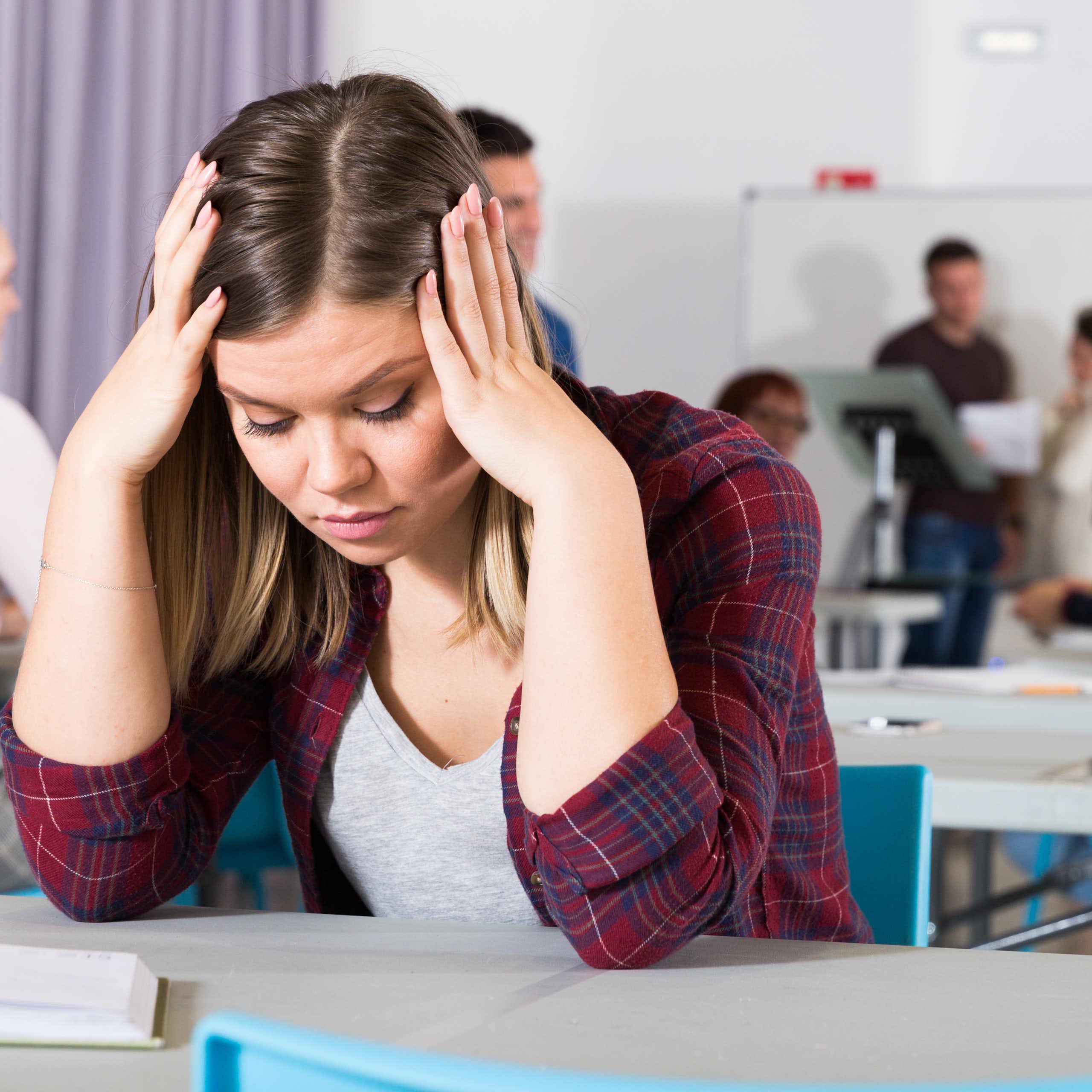 Una joven con gesto de desesperación en un aula.