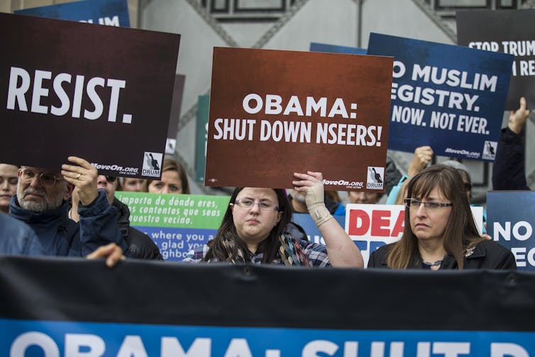 Demonstrators walk as they hold signs.