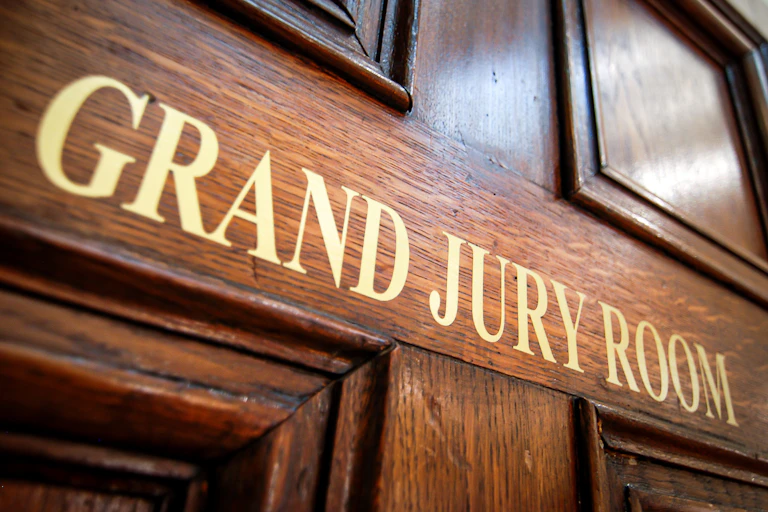 A wooden door with gold print that says 'GRAND JURY ROOM.'