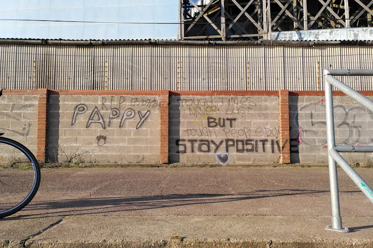 Graffiti on a low wall that reads 'tough times never last but tough people do'
