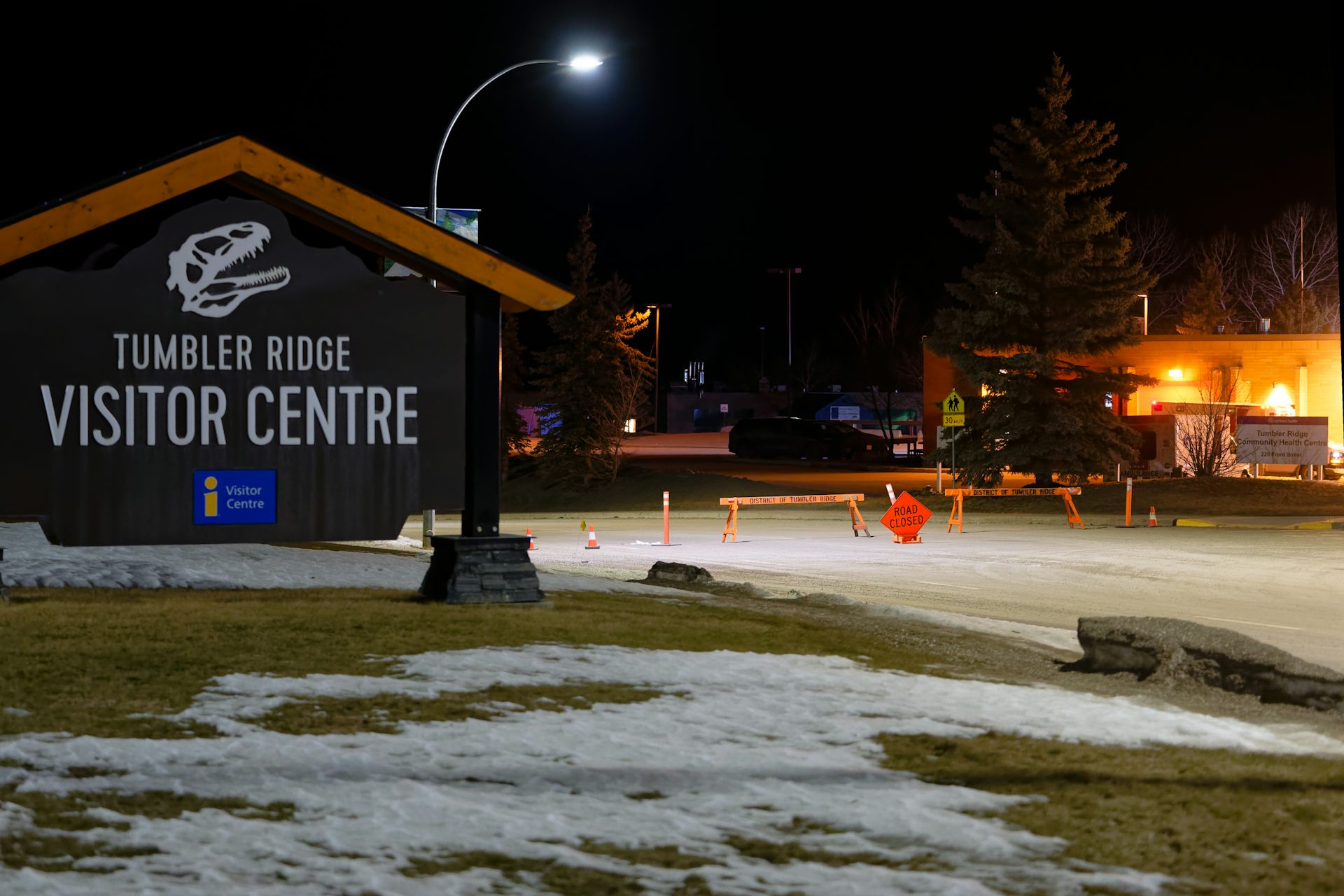 A road closed sign next to flashing amber lights. 