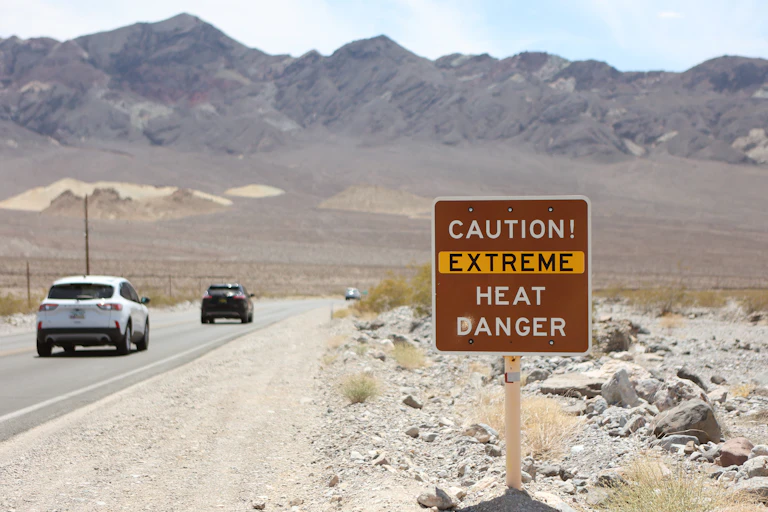 Cars drive past a sign reading 'Caution: Extreme Heat Danger'
