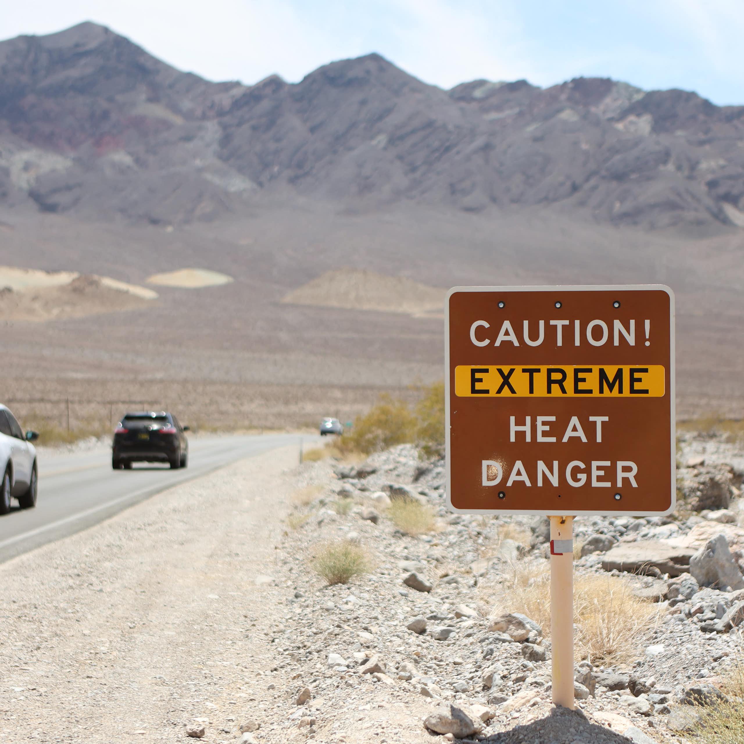 Cars drive past a sign reading 'Caution: Extreme Heat Danger'