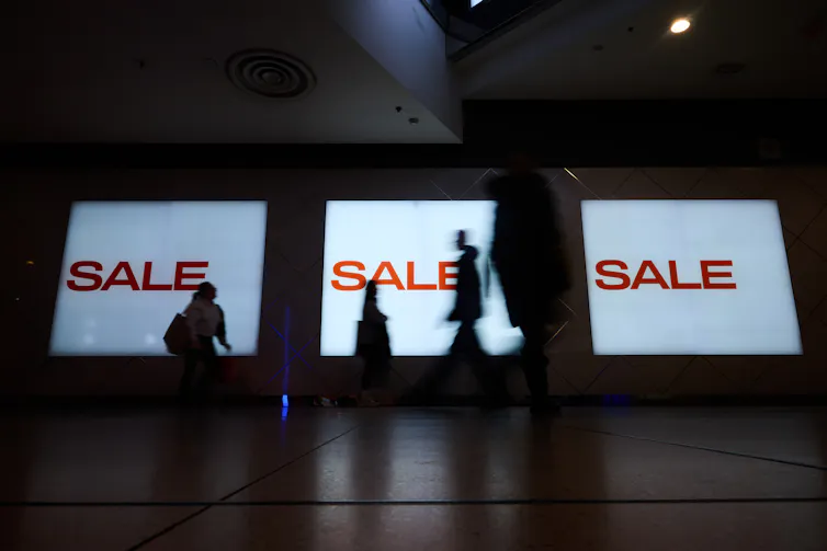 La gente pasa junto a enormes carteles que dicen OFERTA OFERTA