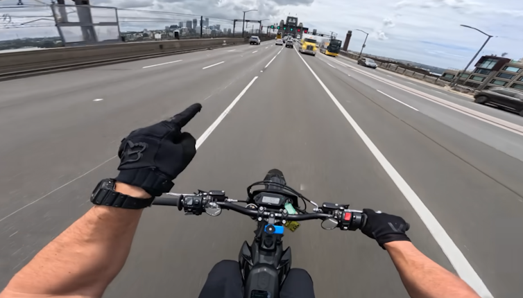 a first person image showing the hands and handlebars of an e-bike rider at high speed on a road