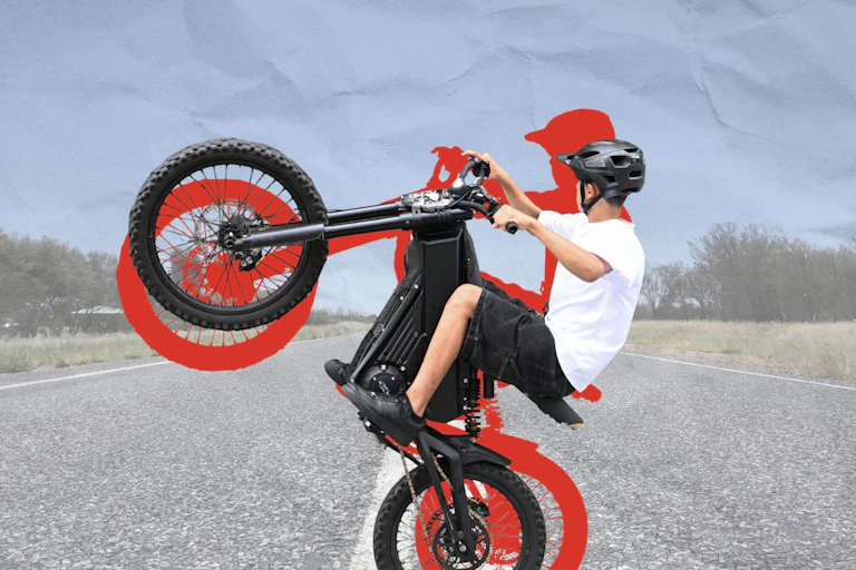 A young boy on an electric bike doing a wheelie