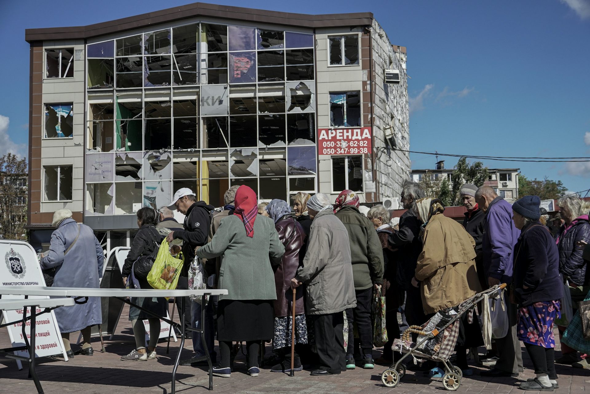 A line of Ukrainians waits to vote in front of a bomb-damaged apartment building, September 2022.