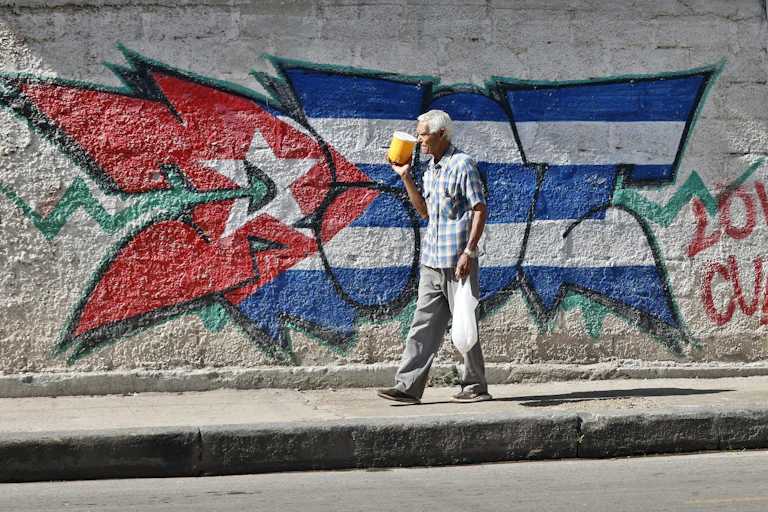 A person walks past a Cuban flag on a street in Havana.