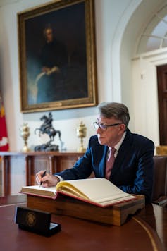 Peter Mandelson signing the White House guest book.