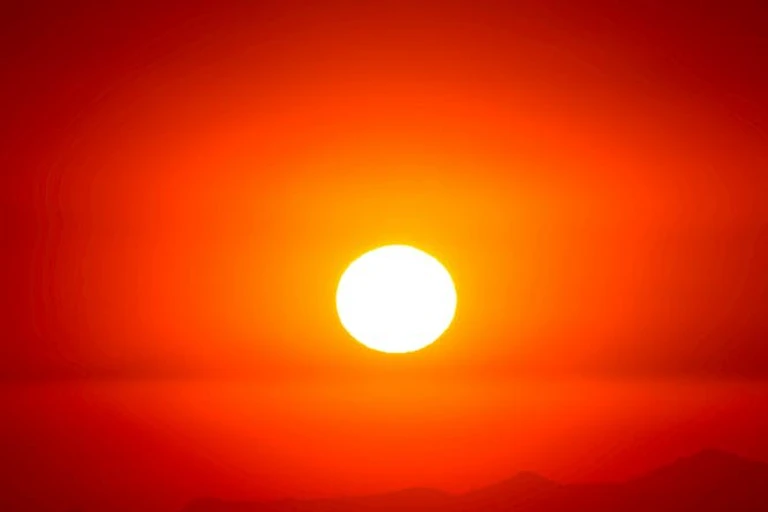 Un soleil brillant et chaud se couche sur un fond orange.