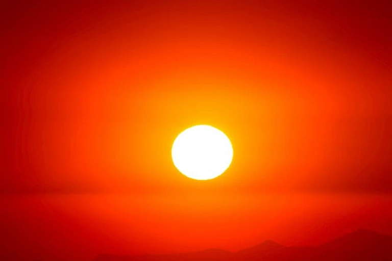 Un soleil brillant et chaud se couche sur un fond orange.