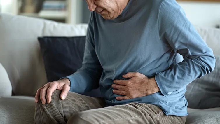 Older man holding his stomach in agony.