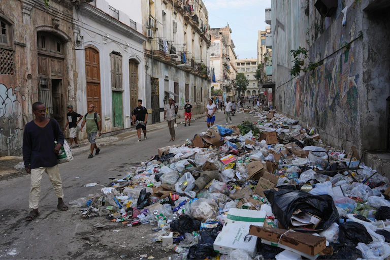 Des gens marchent dans une rue de la ville jonchée de détritus.
