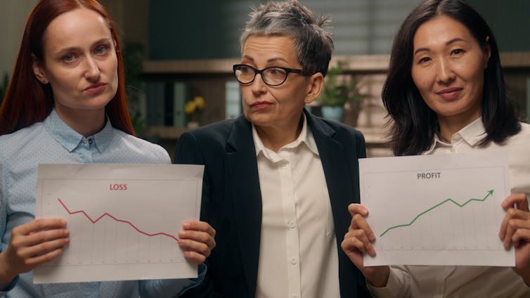 A woman looking sad holding a chart showing a line going down, another looking happy with a chart showing a line going up and a third between them looking confused.