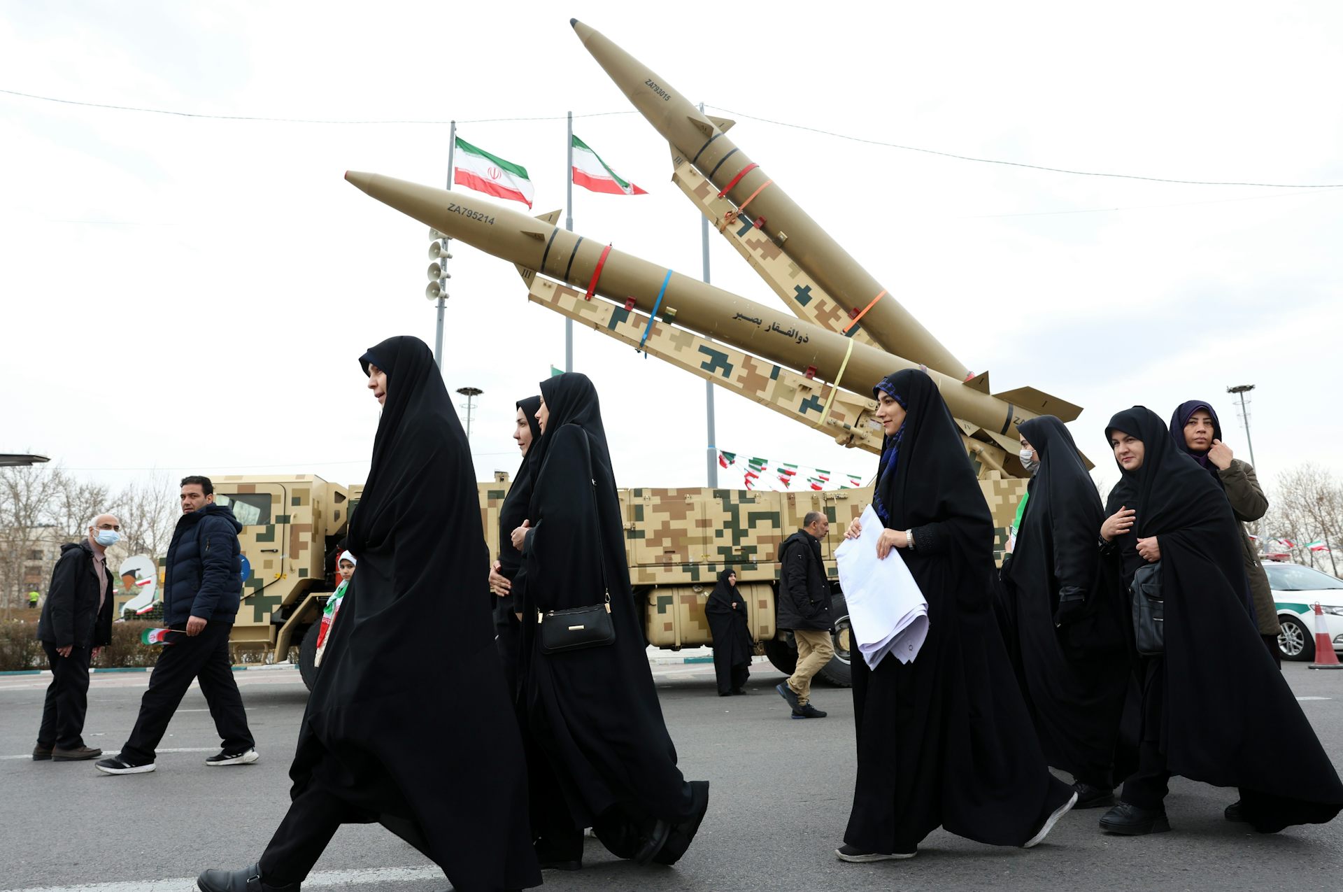 Veiled Iranian women walk next to missiles in Tehran.
