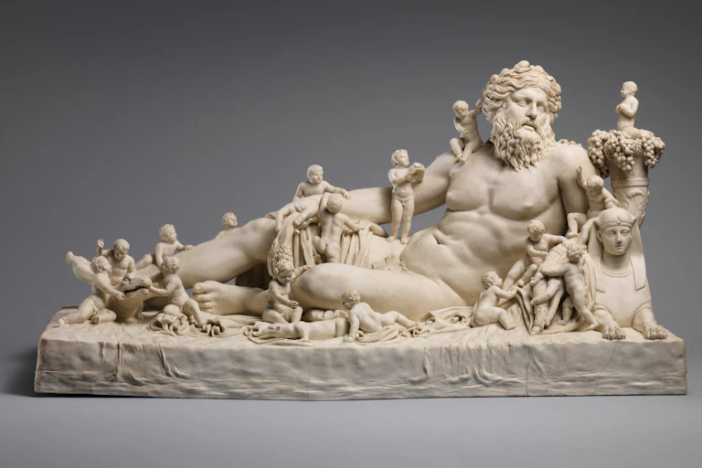 porcelain station of a naked, bearded man reclining with mini children cavorting over and around him