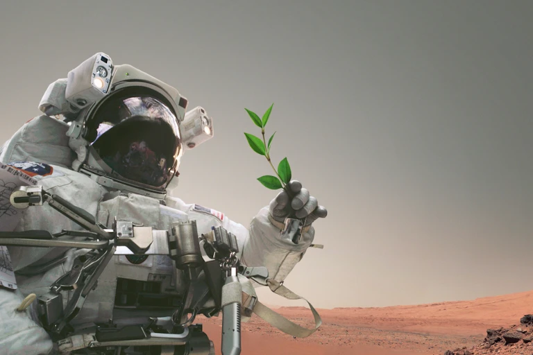 Un astronauta sostiene una planta en Marte