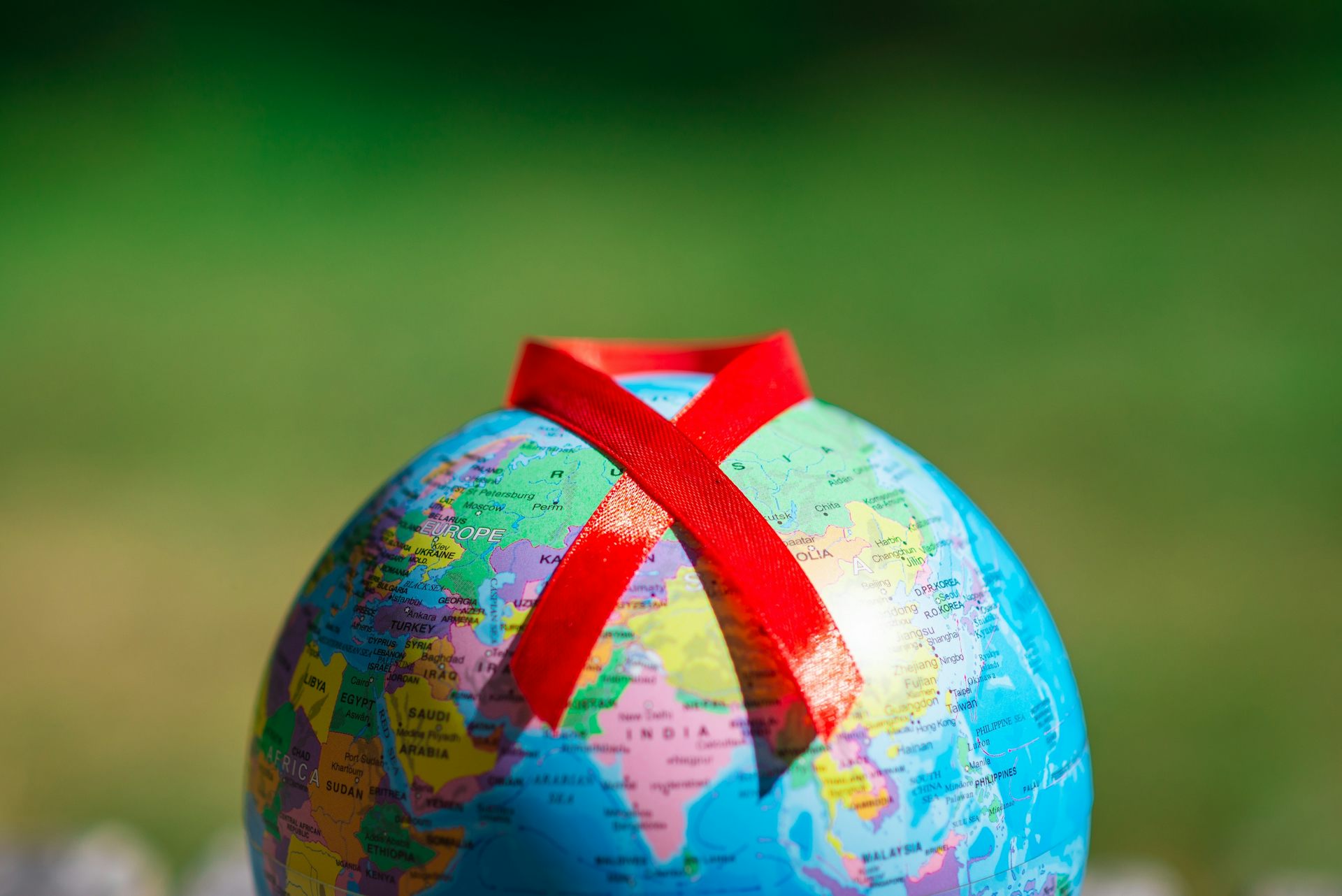 Un globe terrestre sur lequel est posé le ruban rouge symbole de la lutte contre le VIH.
