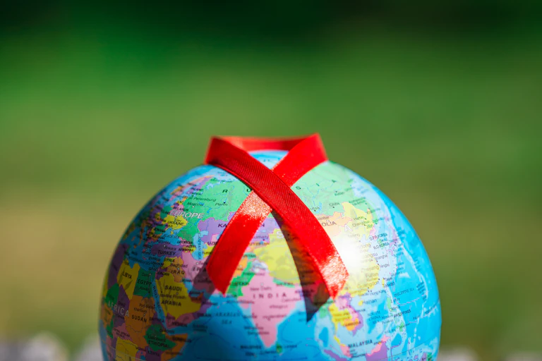 Un globe terrestre sur lequel est posé le ruban rouge symbole de la lutte contre le VIH.