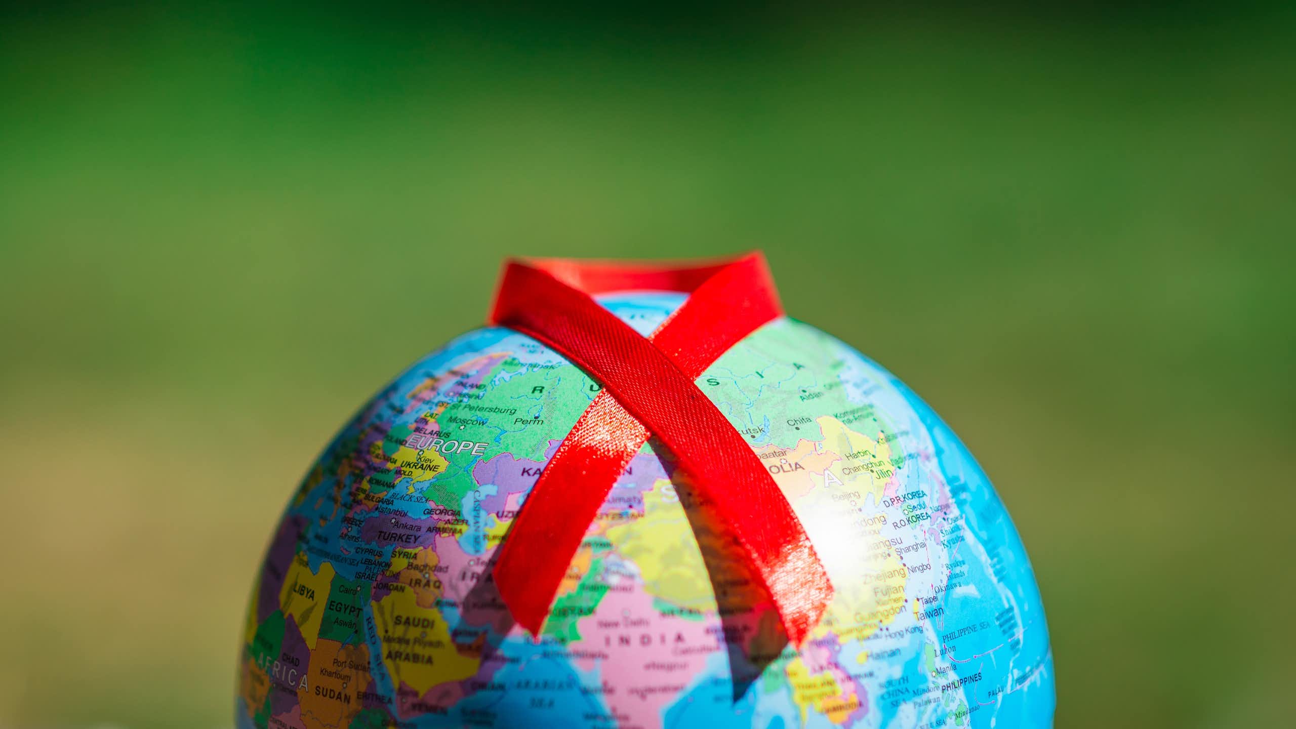 Un globe terrestre sur lequel est posé le ruban rouge symbole de la lutte contre le VIH.