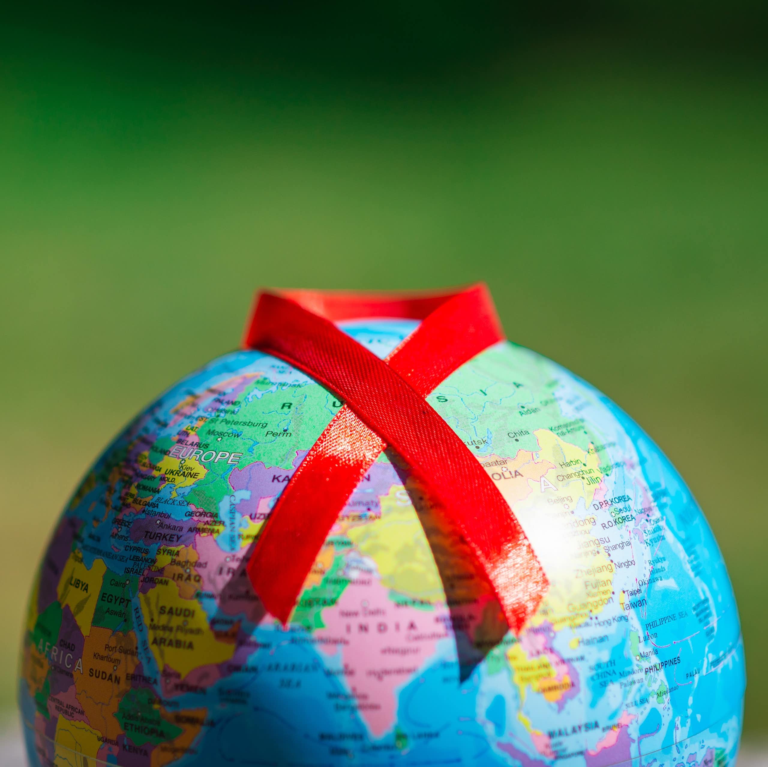 Un globe terrestre sur lequel est posé le ruban rouge symbole de la lutte contre le VIH.
