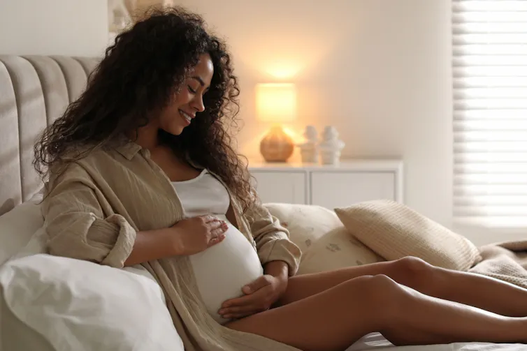 A pregnant woman on a bed.