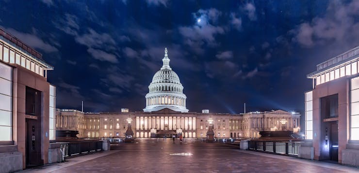 The U.S. Capitol dome in a photo at night with a dark blue sky behind it.