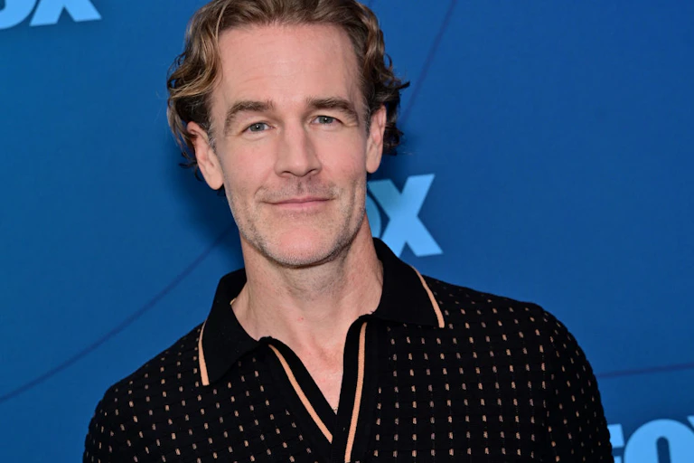 James Van Der Beek smiling into camera, in front of blue press backdrop